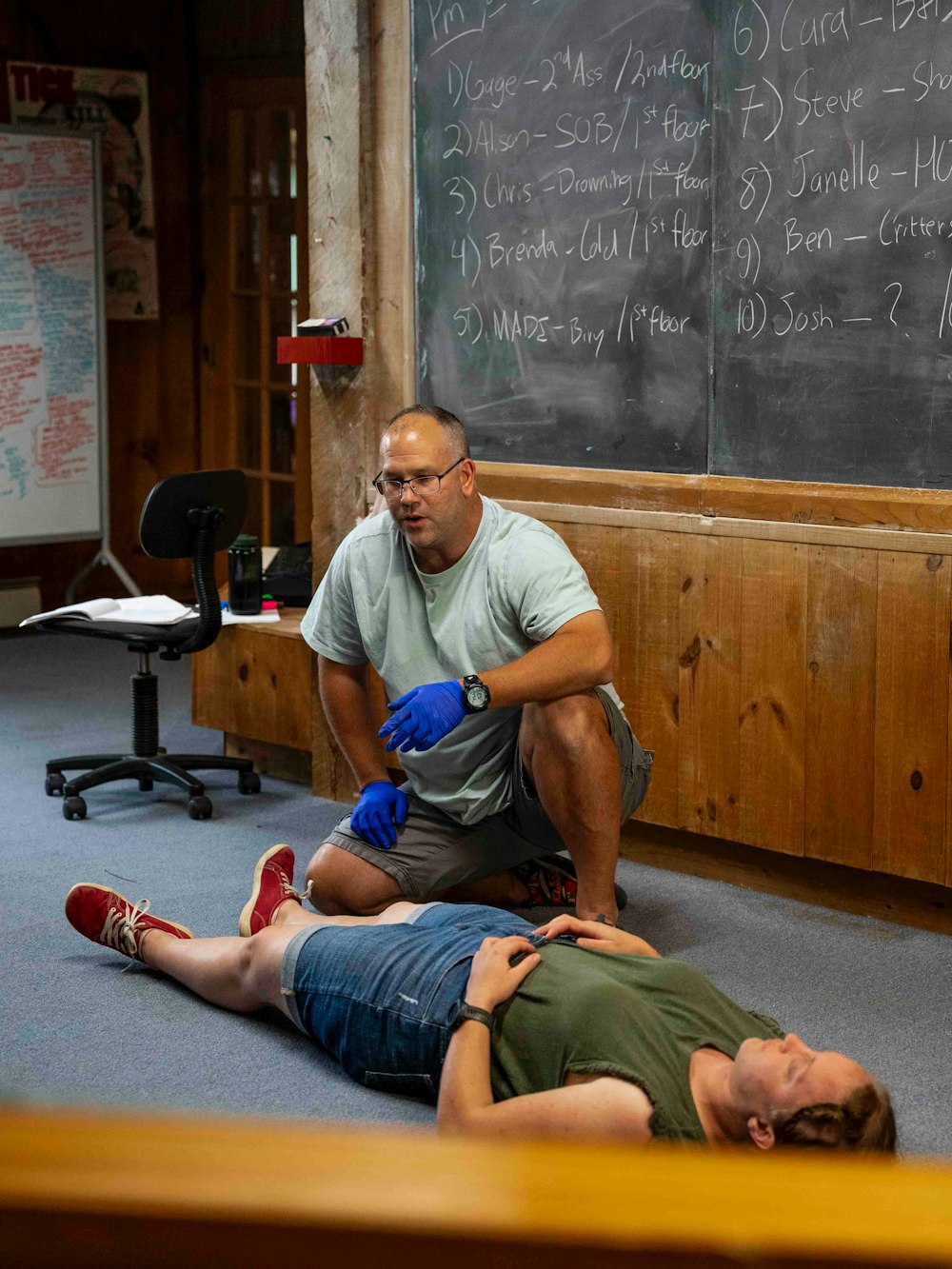 A teacher gently guiding a student's arm into alignment in a standing pose
